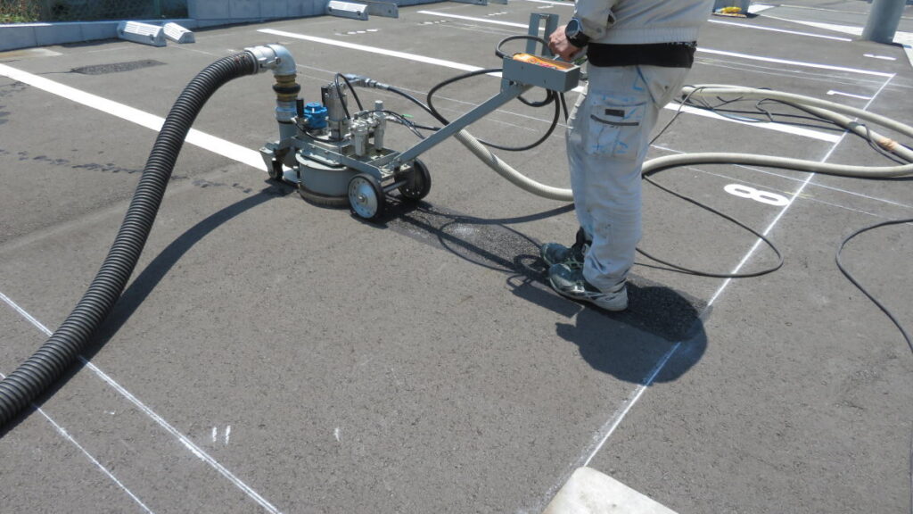 駐車場の区画線をウォータージェットで丁寧に消している様子